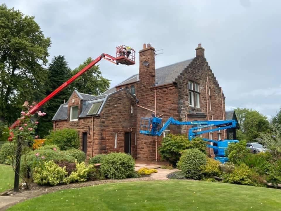 Sandstone villa with cherry pickers in place before cleaning and repointing